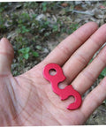 Red aluminum cord buckle for tents, shown on a hand, used as Six Piece Aluminum Cord Buckles For Tent Ropes Quick Knot Adjusters