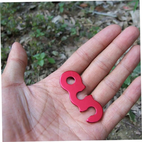 Red aluminum cord buckle for tents, shown on a hand, used as Six Piece Aluminum Cord Buckles For Tent Ropes Quick Knot Adjusters