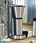 Fully Automatic Bean To Cup Coffee Maker With Integrated Milk Steam Wand, sleek stainless steel design on wooden countertop.