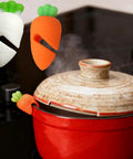 Heavy Duty Silicone Pot Lid Rack And Super Sturdy Cover Lifter Holder for Zero Spill Cooking with colorful carrot designs.