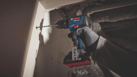 Worker using 18V Brushless Two Tool Combo Kit With Hammer Drill And Driver And Impact Driver Wrench Includes Two 2Ah Batteries For Quick Rugged Power On Any Jobsite on wall