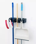 Wall Mount Mop And Broom Holder With 3 Slots And 4 Hooks, space-saving rack holding brooms, brush, and dustpan against white wall
