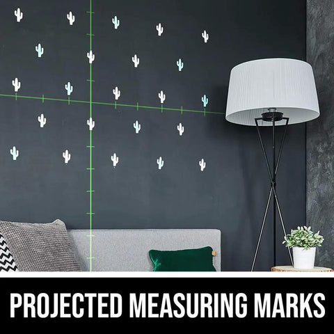 Self Leveling Green Cross Line Laser With Projected Measuring Marks For Quick Precise Layouts Up To 65 Feet A Handy DIY And Pro Tool Red Black LL932401 showing projected green lines with measuring marks on a wall above a couch and floor lamp.
