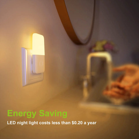 Plug In Night Light With Smart Dusk To Dawn Sensor illuminating a bathroom countertop, showing warm white LED glow, 2 pack