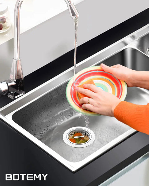 Person rinsing a colorful plate over a kitchen sink with 304 Stainless Steel Kitchen Sink Drain Strainer Assembly Kit For 3.5 Inch Drains Built To Last Heavy Duty Rustproof And Leakproof Basket Stopper With Universal Fit For Standard American Sinks Brushed Finish visible.
