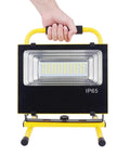 Hand holding JUDYSSY 60/120 W Portable Led Floodlight, IP65 waterproof, showcasing durable design and bright LED array.