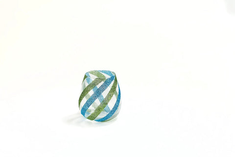 Decorative glass object wrapped in green and blue striped pattern against white background, suggesting creative craft use.