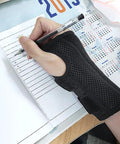 Wrist Brace For Carpal Tunnel Relief, Night Sleep Support For Right Or Left Hand, shown worn on hand while writing, breathable black fabric.