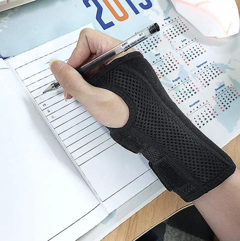 Wrist Brace For Carpal Tunnel Relief, Night Sleep Support For Right Or Left Hand, shown worn on hand while writing, breathable black fabric.