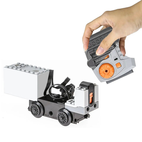 Hand holding remote with 36 Pcs Power Functions Motor Set for STEM Building Blocks, including battery boxes, motors, and wheels.