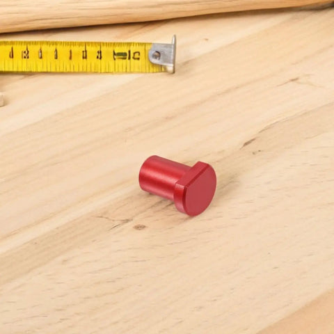 Red aluminum bench dog for woodworking near a tape measure, part of Six Pack Aluminum Bench Dogs For Woodworking With Low Profile.
