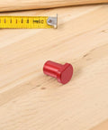 Red aluminum piece from Six Pack Aluminum Workbench Dog Clamps With Low Profile Design Scratch Resistant Surface Easy Install Woodworking Table Stops For Pro Craftsmen next to measuring tape on wooden surface