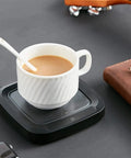 Keep Your Daily Brew Piping Hot With This Smooth Operator Ceramic Coffee Mug Warmer Featuring Fast Ptc Heating Non Slip Base And No Mess Setup Built For Office Or Couch Sweet Sips Always. White ceramic mug on black coffee warmer.