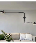 Slick Adjustable Double Head Wall Sconce Lamp In Modern Black Finish With Swivel Pole Design For Cozy Bedroom Reading Vibes And Chic Home Decor Upgrades mounted above a sofa.