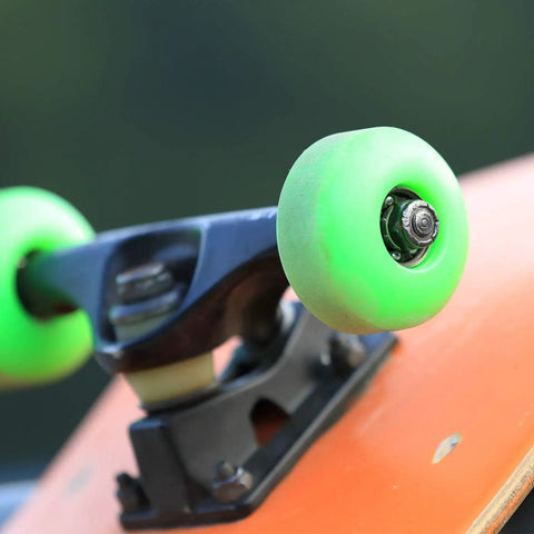 Close-up of a skateboard wheel and truck featuring a skateboard truck hardware kit with 8 spacers 8 axle nuts and 40 speed rings for skateboards.