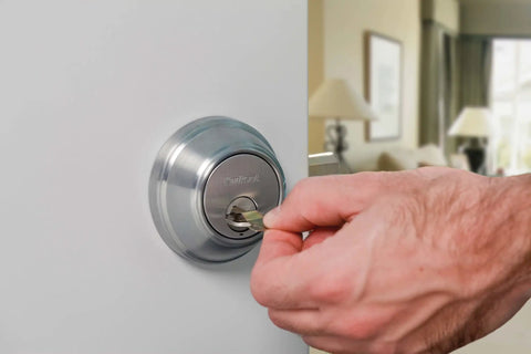Close-up of hand using key in SmartKey Security Exterior Deadbolt With Keyed Entry In Satin Nickel Model 980 on a door