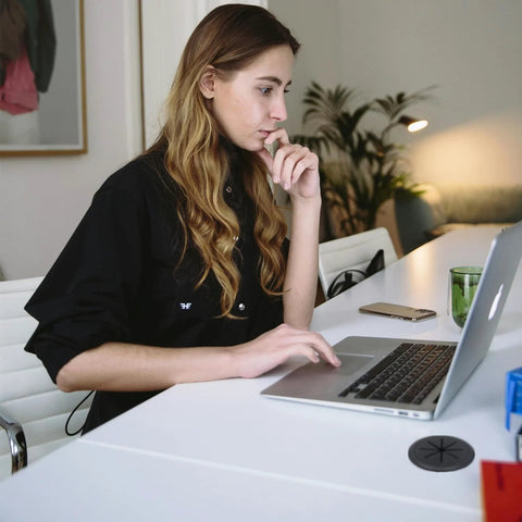 Woman working at desk with 2 Pack Desk Grommet 2 Inch 50 Mm Hole Cover For Cables Black Desk Cord Hole Cover visible on table