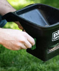 Person using Handheld Seed Spreader for Lawns and Gardens With 6 Lb Capacity, Easy Grip Angle Handle, Durable All Season Design outside.