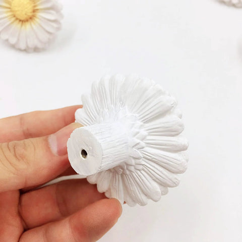 Hand holding Daisy Design Vintage Resin Drawer Pull, showcasing hand-painted white resin, for country kitchen cabinets.