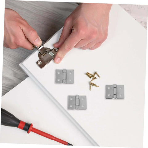 Two metal barn door hinges being installed on a white wooden door panel; screws and screwdriver nearby