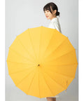 Woman holding yellow umbrella with long handle and wide coverage against plain background