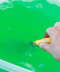 Hand mixing Green Concrete Dissolver Foam Spray 22oz, Biodegradable Non Corrosive Formula solution in a plastic container.