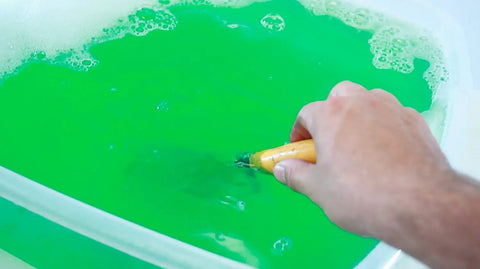 Hand mixing Green Concrete Dissolver Foam Spray 22oz, Biodegradable Non Corrosive Formula solution in a plastic container.