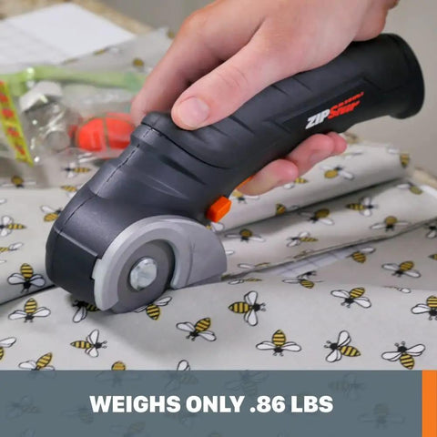 Close-up of Zip Snip Cordless Electric Scissors cutting bee-patterned fabric, highlighting its lightweight design and clean cuts.