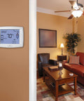 Ultra Easy Read Touchscreen 7 Day Programmable Thermostat with 12 Inch Display mounted on living room wall, showing temperature.