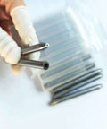 Close-up of stainless steel abrasive water jet nozzle tips held by gloved hand; six nozzles visible in background