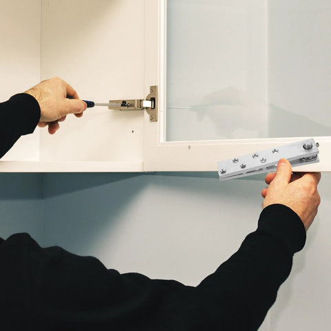 Person installing heavy duty 360-degree hidden pivot door hinges for wooden cabinets and secret bookcase, stainless steel.