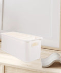 Slick White PP Plastic Drawer Organizer Box With Comfortable Handle Grip For Quick Sorting Bras Socks Ties And Everyday Gear To Keep Your Room Neat On The Daily on a wooden surface.