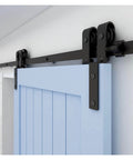 Heavy Duty Sliding Barn Door Hardware Kit For Double Doors Bypass Track System With Bent Hangers Anti Jumping Block Floor Guide Space Saving Durable 6.6 Foot Track For Easy Install And Quiet Smooth Operation, showing a black metal track with bent hangers installed on a blue door.