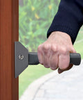 Hand gripping the Doorway Flip Assist Handle Grip Bar for Easy Step Through, Stability Boost for Hallways and Doors, black metal