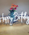 Birthday Neon Sign LED Wall Backdrop 23.6x9.45 Inches Custom Party Neon Light displayed in front of a vase with flowers on a table.