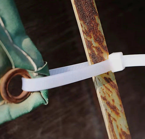 Close-up of 15 Inch Zip Ties White securing rusted metal and fabric, UV resistant, for outdoor and indoor use.