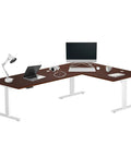 Electric Motorized Corner Desk, Massive L Shaped Standing Workstation With Smooth Ride Height Adjustments, Rock Solid White Frame On Premium Dark Cherry Desktop with a laptop and monitor.