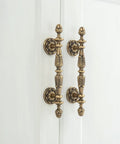 Five Pack Antique Brass Cabinet Handles With 3.4 Inch Hole Centers installed on a white cupboard door