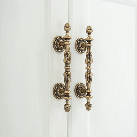 Five Pack Antique Brass Cabinet Handles With 3.4 Inch Hole Centers installed on a white cupboard door