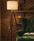 Vintage Tripod Floor Lamp With Nautical Vibe And Dope Rustic Industrial Finish In Steel Aluminum And Brown Wood Antique Brass Accent Shade Not Included Perfect For Living Room Decor Or Gift in cozy living room setting with green armchair and open book.
