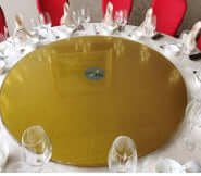 63" Gold Tempered Glass Heavy Duty Lazy Susan - Turntable Bearing Base on a dining table with elegant glassware.