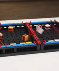 Slide Battle Building Kit With 102 Components For Big Kids And Adults Who Love To Build And Create, Ages 7 And Up, A Smart Expansion For Your Build Your Own Game Set, Perfect For Get Your Game On Competitive Play And Brain Boosting Fun. hands playing on a tabletop build game board with plastic pieces