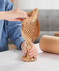 Person stretching 15 Inch By 213 Foot Honeycomb Packing Paper Bubble Wrap For Packing Shipping And Moving on table