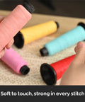 Person holding pink thread spool near Matte Embroidery Thread 40WT Low Sheen Polyester For Embroidery Machines 2500M Spools