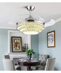 42 Inch Retractable Blade Ceiling Fan Featuring Glowing Crystal Chandelier And Smart Remote Controls For Tunable LED Lights in stylish dining room.