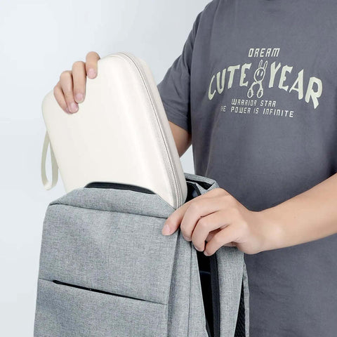 Person placing a white Hard Shell Cable Tech Organizer Travel Case For Power Banks And Portable Chargers into a gray backpack.