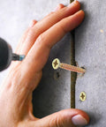 Installation of Heavy Duty Steel Hollow Wall Anchors With Screws Kit for Drywall and Plaster Walls, close-up view of screwing process.