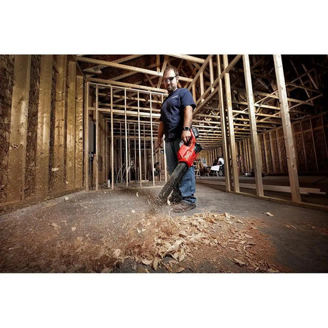 Person using M18 FUEL Cordless Handheld Blower With 120 MPH Air, 450 CFM Power in a construction setting, red and black tool.