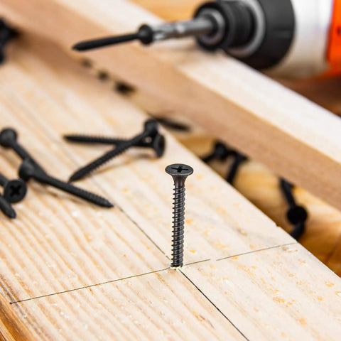 Heavy Duty Workhorse 6 X 1 1/4 Fine Thread Drywall Screw self-tapping in wood, showcasing solid black phosphate coating.