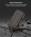 Rugged Water Resistant Camera Battery And Card Case shockproof in black and orange, demonstrating durability on cracked pavement.